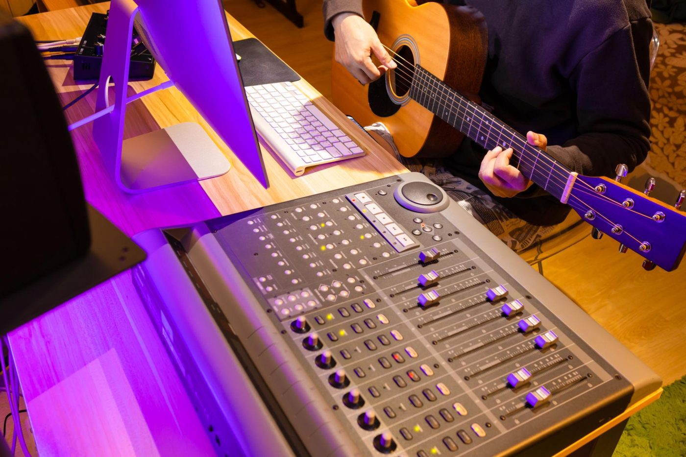 A guitarist and a mixing desk in a music studio