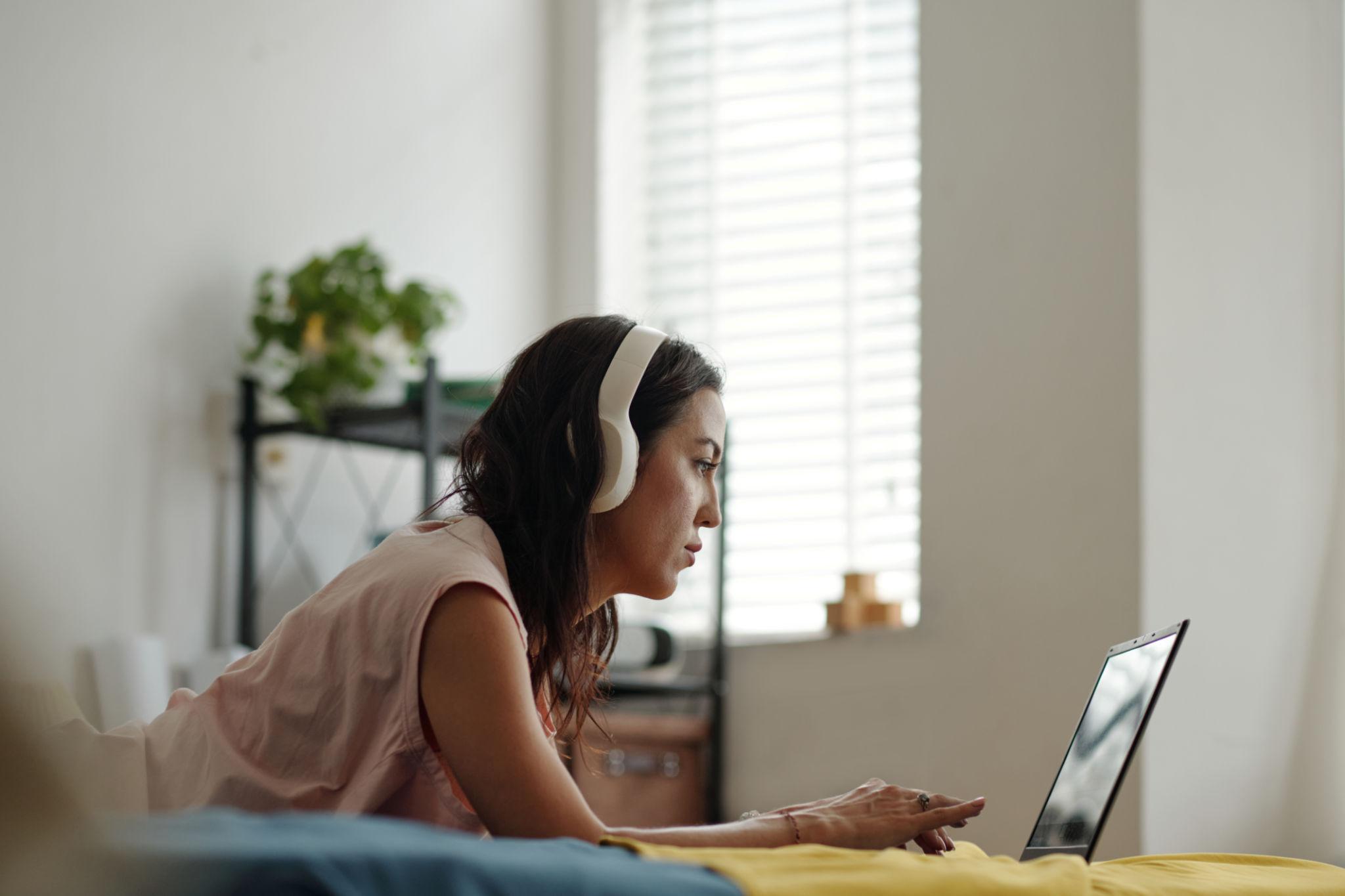 A musician wearing headphones working on songs on a laptop